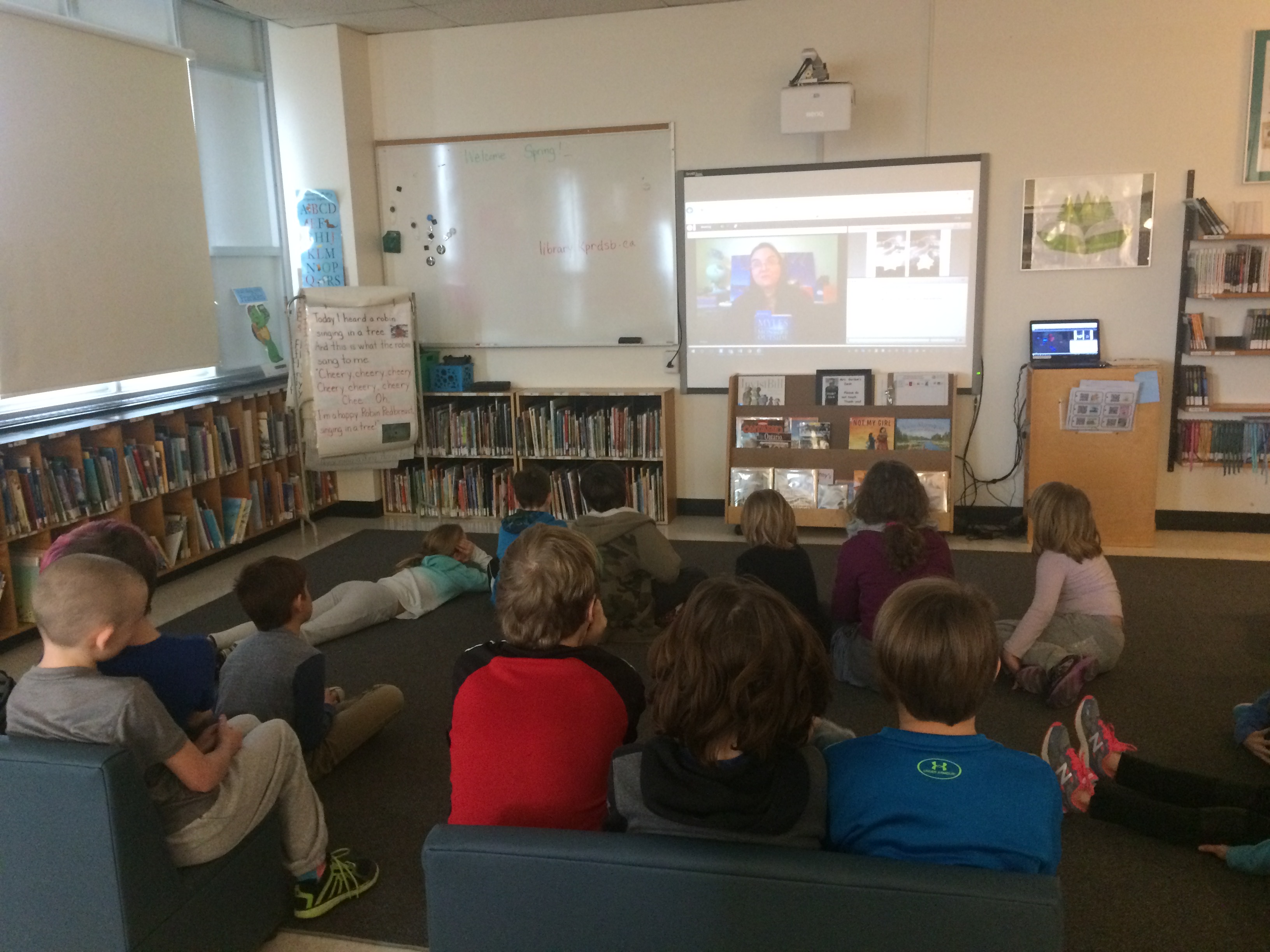 students in library watching a virtual author visit from Smartboard
